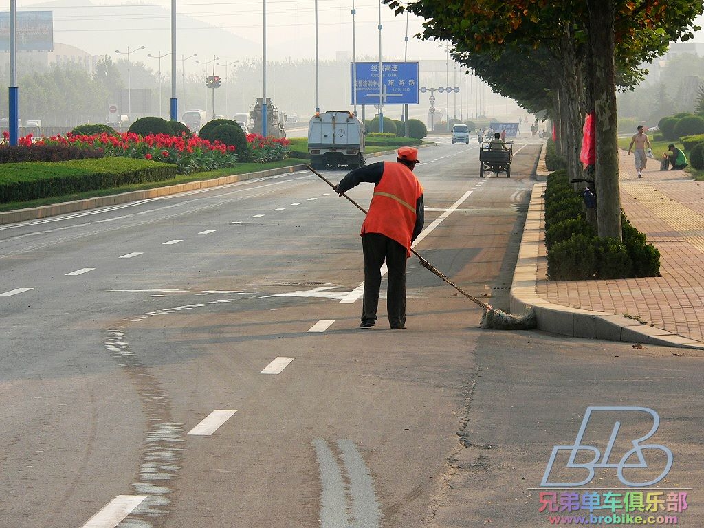 路边，一位环卫工人在清扫落叶