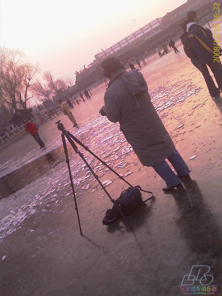 凿开的冰面，旁边是一貌似专业的摄影者